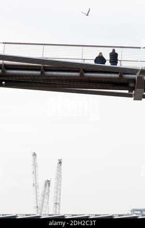 Vue à angle bas de deux personnes appréciant la vue de Millennium Bridge avec des grues de construction en arrière-plan, Londres Banque D'Images