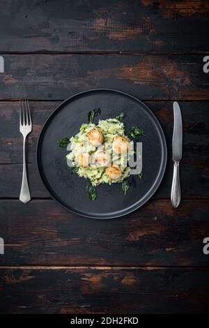 Fruits de mer, noix de Saint-Jacques grillées avec des pommes de terre et des pois, vue de dessus, sur fond de bois foncé avec espace pour les copies Banque D'Images