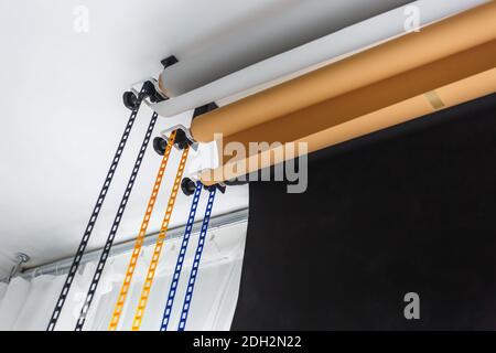 système de support manuel de montage pour les dorlotages photo dans un studio moderne. Des rouleaux d'arrière-plans en papier coloré pour studio photo sont accrochés au mur Banque D'Images