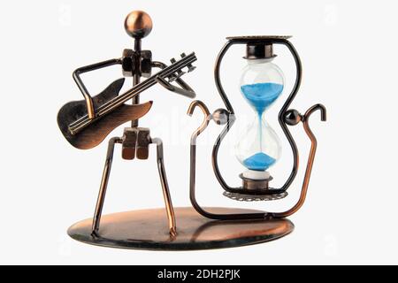 HourGlass dans un coffret métallique et sable bleu. À côté de la figure d'un homme avec une guitare. Isolé sur un fond blanc Banque D'Images