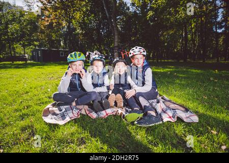 Grande famille d'enfants de race blanche. Trois frères et sœurs assis sur une couverture à l'extérieur du parc. Herbe verte de pelouse de backgro Banque D'Images