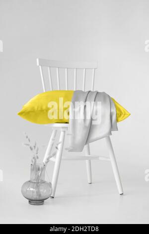 Arrière-plan minimaliste en 2021 couleurs tendance. Gris et jaune. Une chaise avec un coussin jaune contre un mur gris. Banque D'Images