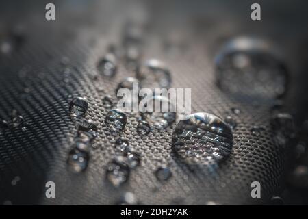 Beaucoup de gouttes d'eau sur tissu imperméable imprégné de parapluie noir. Banque D'Images