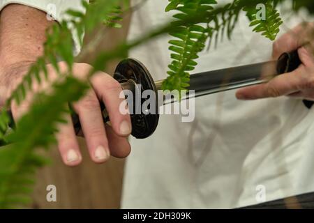 Les mains des hommes prennent une épée katana japonaise Banque D'Images