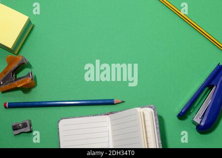 Modèle à arrière-plan vert avec des objets de papeterie tels que des agrafeuses, des stylos, des carnets Banque D'Images