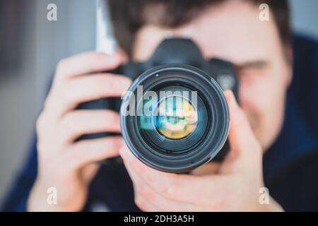 Photographe au travail : l'homme est debout derrière un appareil photo professionnel sur un trépied, pour prendre des photos Banque D'Images