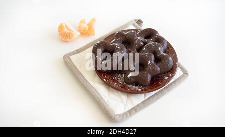 Pain d'épice fait maison recouvert de chocolat sur plaque de céramique brune, tranches de clémentine, fond blanc Banque D'Images