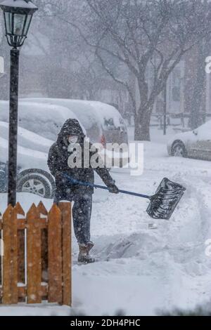 Toronto, Canada, décembre 2007 - un homme en veste noire et capuche enlève la neige de devant sa maison avec une pelle pendant une tempête de neige Banque D'Images