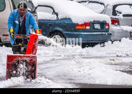 Toronto, Canada, janvier 2008 - un homme d'origine noire qui défrichement la neige avec une souffleuse à neige dans un stationnement de résidence Banque D'Images