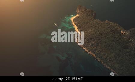 Coucher de soleil en haut de l'île tropicale vallonnée sur l'océan golfe en vue aérienne. Le soleil se couche à la lumière de la forêt tropicale sur l'île de Palawan, aux Philippines. Paysage marin bleu foncé spectaculaire sur un tir de drone à lumière douce Banque D'Images