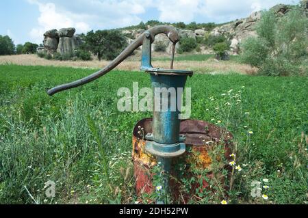 pompe à eau ancienne dans un champ vert Banque D'Images