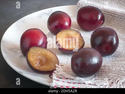 Grandes prunes mûres sur une assiette blanche Banque D'Images