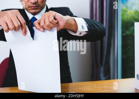 Homme d'affaires en colère déchirant le document papier sur le bureau Banque D'Images