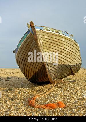 La coque d'un vieux bateau de pêche a laissé haut et sec sur la plage de galets à Dungeness. Un certain nombre de ces bateaux abandonnés sont dispersés ici. Banque D'Images