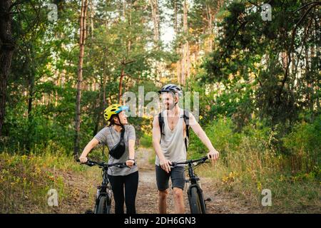 Magnifique couple en vélo dans la forêt du parc. Voyage romantique à vélo. Week-end actif. Couple sport. Homme et femme cyclistes. Banque D'Images