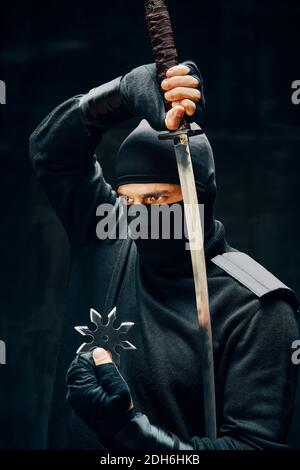 Combattant guerrier ninja samouraï avec une épée et shuriken plus arrière-plan noir Banque D'Images