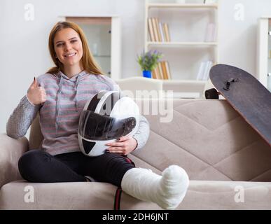 Jeune femme avec jambe cassée à la maison Banque D'Images