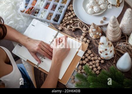 La vue de dessus de la jeune femme écrit des objectifs pour Nouveau Journal de l'année 2021 sur le bureau avec arbre de Noël Banque D'Images