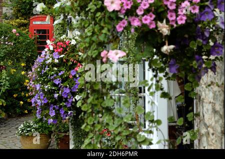 Cabine téléphonique rouge avec fleurs sur le mur Banque D'Images