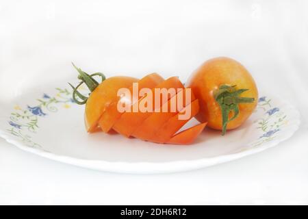 Tomates mûres ou tomates cerises, isolées sur fond blanc. Tranche de tomate fraîche et tomates à la griffe sur blanc. Ingrédients de cuisson Banque D'Images