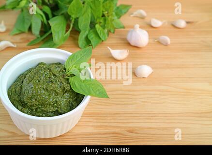 Bol de sauce pesto au basilic frais maison avec ingrédients flous Sur fond en bois Banque D'Images