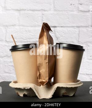 Deux tasses jetables en papier marron avec support de couvercle en plastique dans le bac Banque D'Images