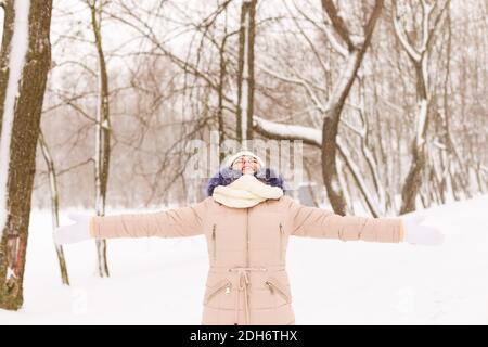 Jeune fille dans une forêt enneigée en hiver. Portrait d'une fille dans un parc d'hiver avec de la neige courante. Une femme attrape des flocons de neige Banque D'Images