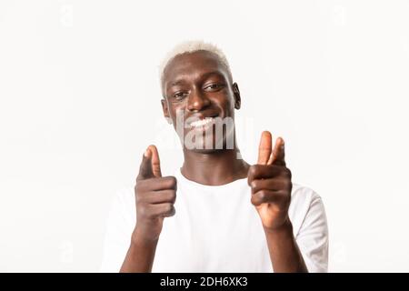 Gros plan d'un beau gars blond afro-américain de soutien pointant les doigts vers la caméra et souriant, félicitant, félicitant bien Banque D'Images