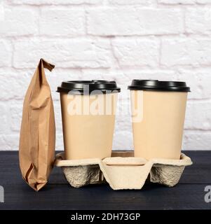 Deux tasses jetables en papier marron avec support de couvercle en plastique dans le bac Banque D'Images