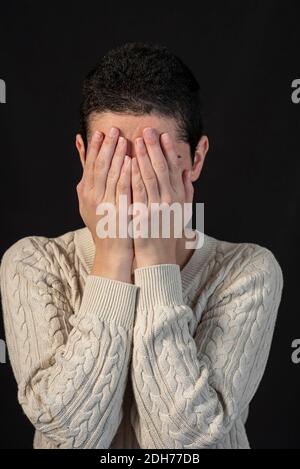 Jeune femme stressée avec des cheveux courts se cachant le visage avec les mains Banque D'Images