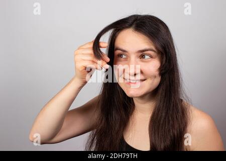 La fille montre les bangs cultivés. Soins des cheveux, longues langes. Croissent les langes. Banque D'Images