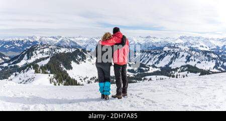 Le couple Senior fait de la randonnée dans les montagnes d'hiver de la neige alpine et bénéficie d'une vue panoramique. Allgau, Bavière, Allemagne. Banque D'Images