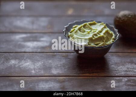 Guacamole à la sauce mexicaine traditionnelle latinaméricaine dans un bol et avocat sur fond sombre avec espace pour les copies. Banque D'Images