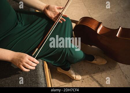 Adolescente avec son violoncelle, posant dans une salle. Banque D'Images