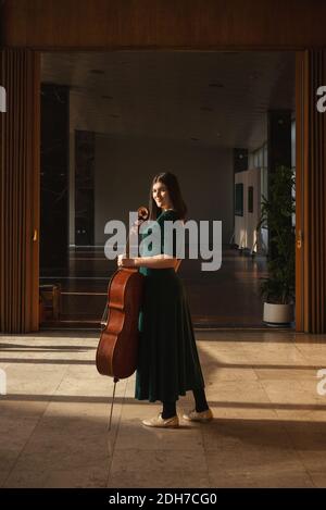 Adolescente avec son violoncelle, posant dans une salle. Banque D'Images