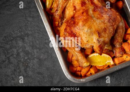 Poulet entier cuit avec carottes et oranges sur une table en bois. Vue rapprochée et vue de dessus. Photo de haute qualité Banque D'Images