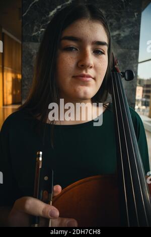 Adolescente avec son violoncelle, posant dans une salle. Banque D'Images