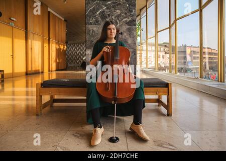 Adolescente avec son violoncelle, posant dans une salle. Banque D'Images