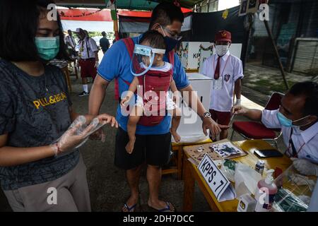 Tangerang Sud, Indonésie. 9 décembre 2020. Un fonctionnaire donne de l'encre comme marque à un homme portant un masque facial après avoir fait un bulletin de vote dans un bureau de vote lors de l'élection régionale 2020 à South Tangerang, Indonésie, le 9 décembre 2020. Credit: Agung Kuncahya B./Xinhua/Alay Live News Banque D'Images