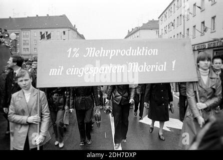 01 mai 1982, Saxe, Eilenburg : « un pour cent de production en plus avec des matériaux économisés ! » Lors de la manifestation à Eilenburg, le 1er mai 1982, des ouvriers, des écoliers, des sportifs, des femmes et des enfants défilent devant l'hôtel de ville et une tribune avec des invités d'honneur s'y est établie. Photo: Volkmar Heinz/dpa-Zentralbild/ZB Banque D'Images