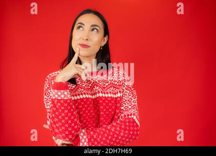 Jeune belle femme portant un chandail décontracté sur fond rouge isolé confusion et se demandant au sujet de la question. Incertain avec doute, pensant avec ha Banque D'Images
