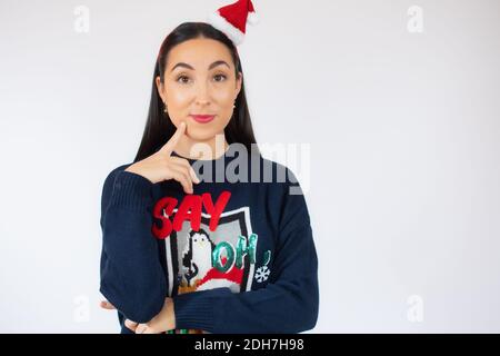 Jeune belle femme portant chapeau de santa sur fond blanc isolé confusion et se demandant au sujet de la question. Incertain avec le doute, pensant avec la main Banque D'Images