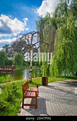 Un banc et une poubelle dans un parc public. Banque D'Images