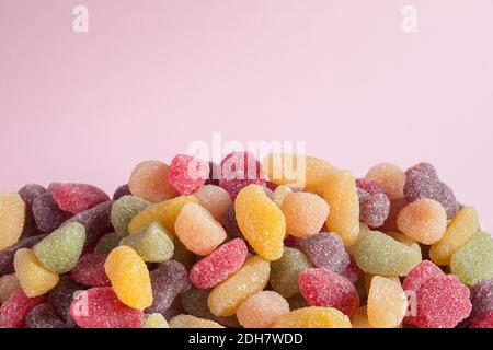 Beaucoup de bonbons colorés avec du sucre sur fond rose éclairé. Banque D'Images