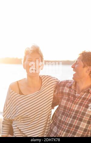 Couple heureux appréciant sur la plage pendant le coucher du soleil contre ciel clair Banque D'Images