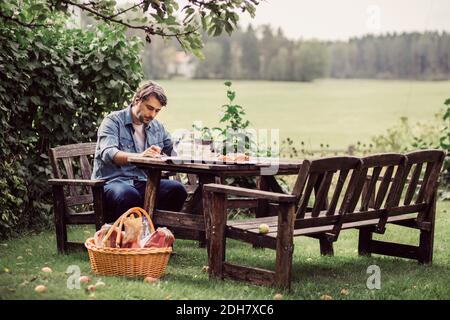 Homme adulte de taille moyenne prenant le petit déjeuner à table dans une ferme biologique Banque D'Images