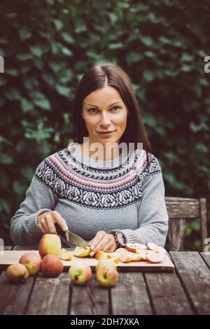 Portrait d'une femme adulte de taille moyenne coupant des pommes à la table ferme biologique Banque D'Images