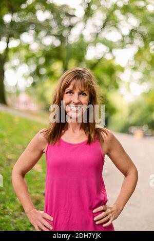 Portrait d'une femme mûre et heureuse debout hanches au parc Banque D'Images