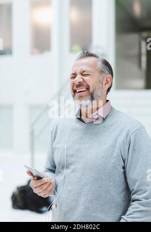 Un homme d'affaires rit tout en communiquant avec un casque au bureau Banque D'Images