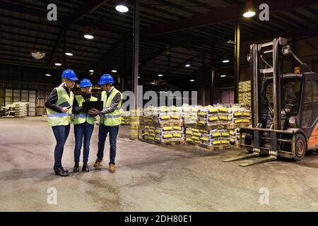Toute la longueur des travailleurs manuels utilisant un ordinateur portable dans l'entrepôt de ciment Banque D'Images